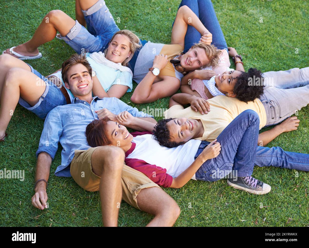 Theyre a close group of friends. High angle of a group of friends lying on their backs on the grass in a park. Stock Photo