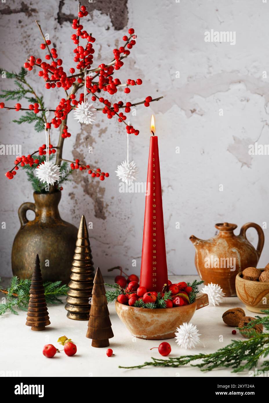 Burning Advent calendar candle with December month date 24 numbers and red holly ilex branch. Christmas home decoration concept. Copy space. Stock Photo