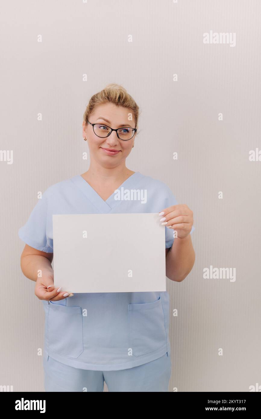 Portrait of a female doctor in a blue robe holding a white blank sheet Stock Photo