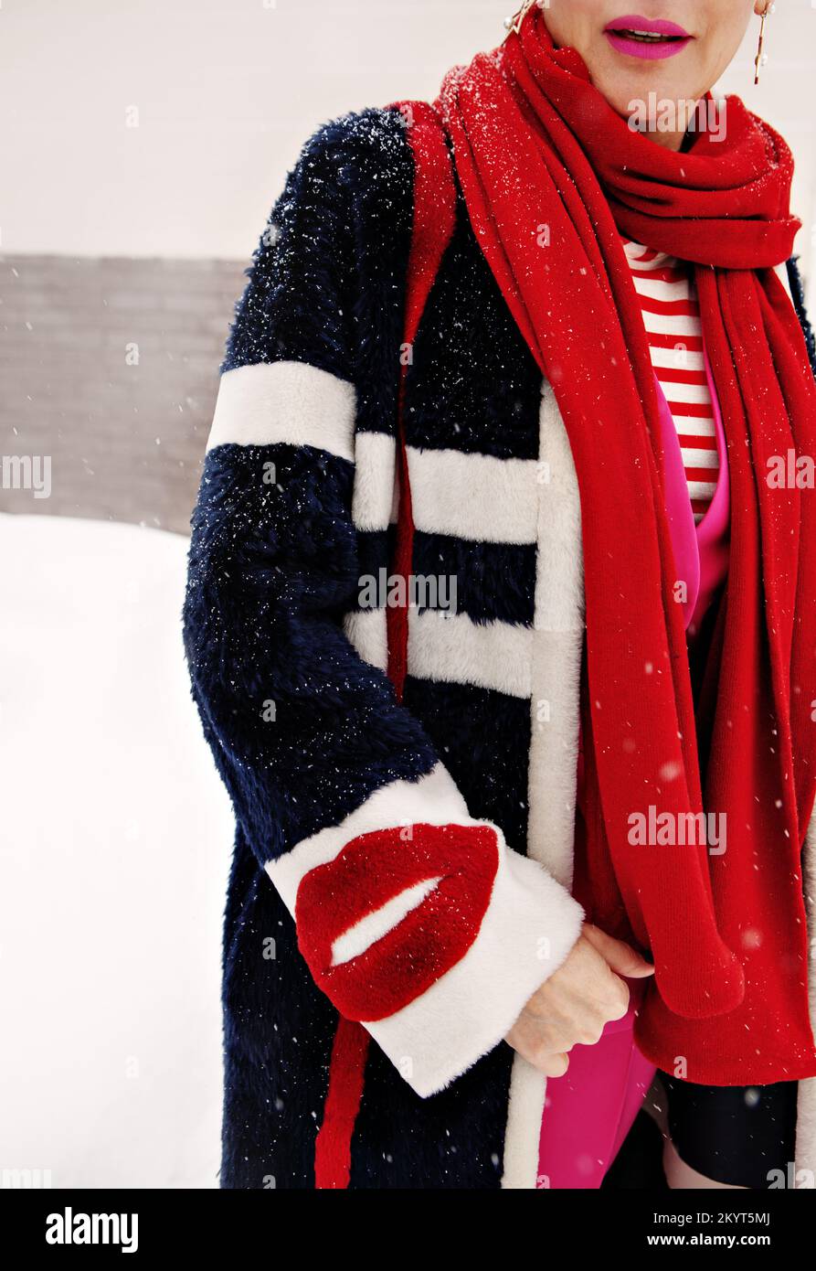 Woman hand in fake fur jacket with lips, stylish female sleeve detail in red scarf and fashionable coat Stock Photo