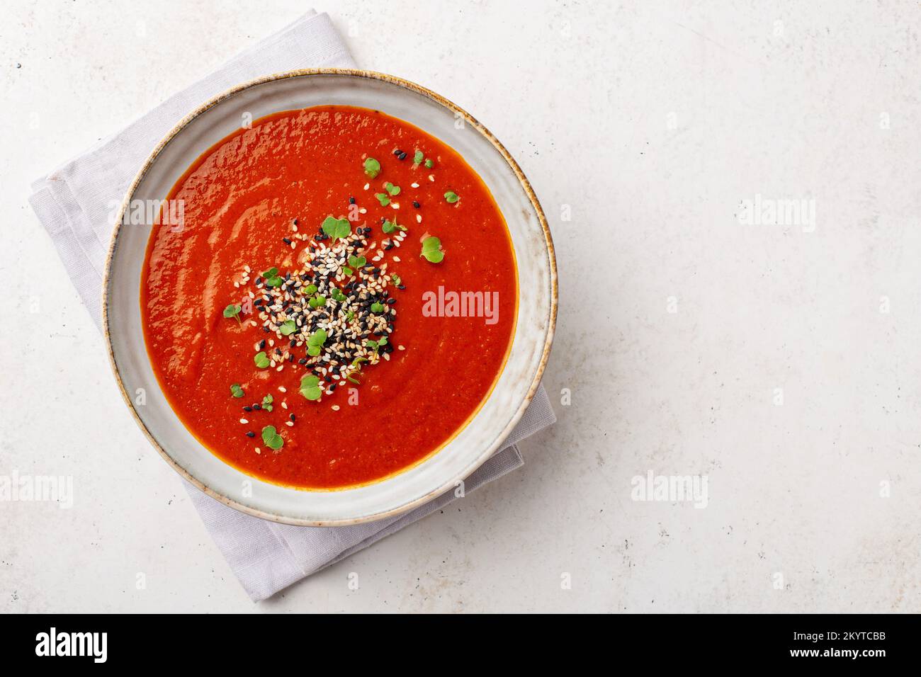 Overhead shot of a bowl full of creamy vegetarian soup served with micro greens, with space for text Stock Photo