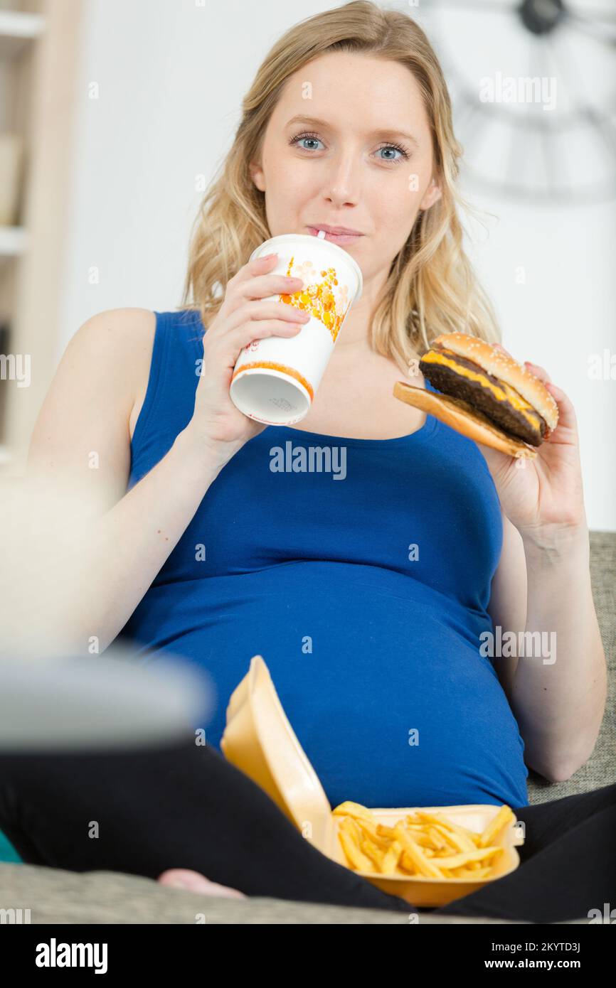 pregnant woman with belly is holding a burger Stock Photo