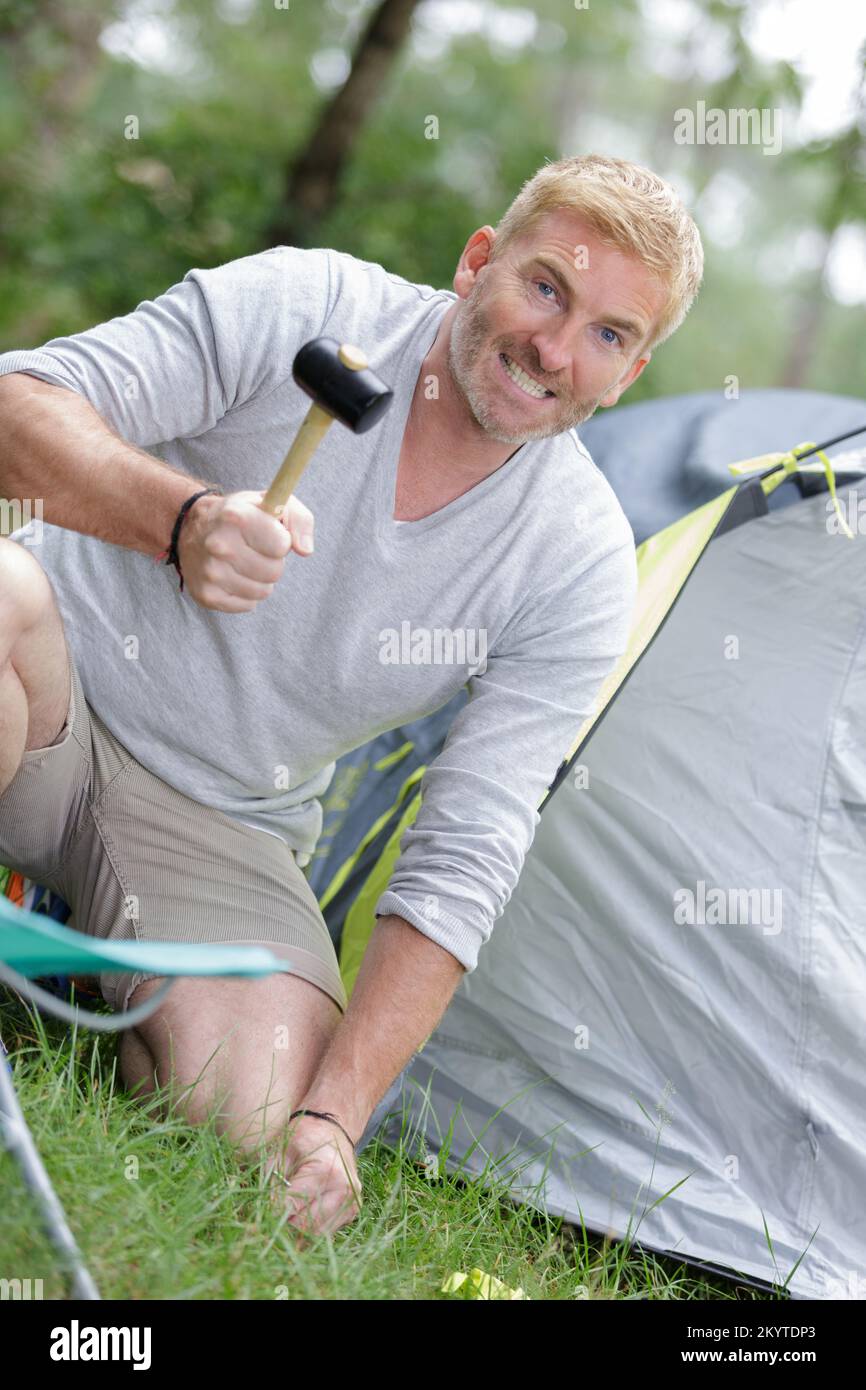 man using a hammer to setup tent for camping Stock Photo Alamy
