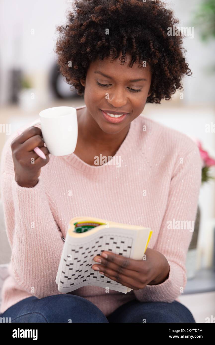 woman sitting on sofa doing crosswords at home Stock Photo Alamy