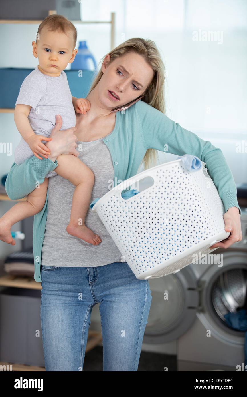 mother and baby loading clothes into washing machine Stock Photo Alamy