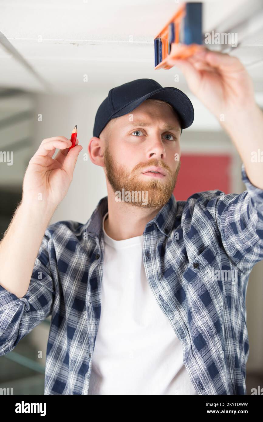 contractor taking ceiling measures with spirit level Stock Photo