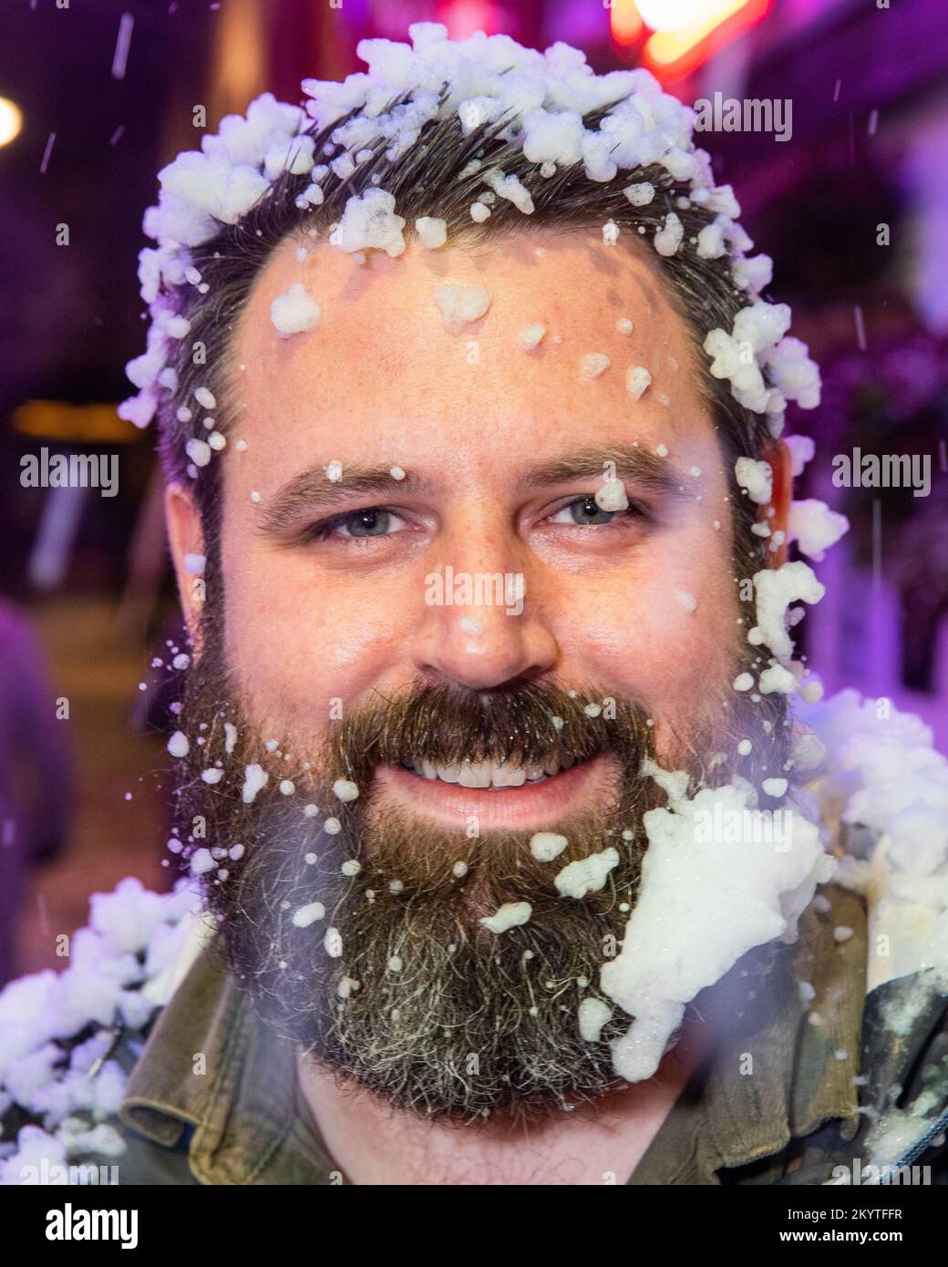 Chris Laughlin on the cobbled streets of Commercial Court outside the Duke of York bar in Belfast as Guinness brought its iconic Christmas ad to life with a snow machine as guests were treated to a pint to start the festive season. Stock Photo