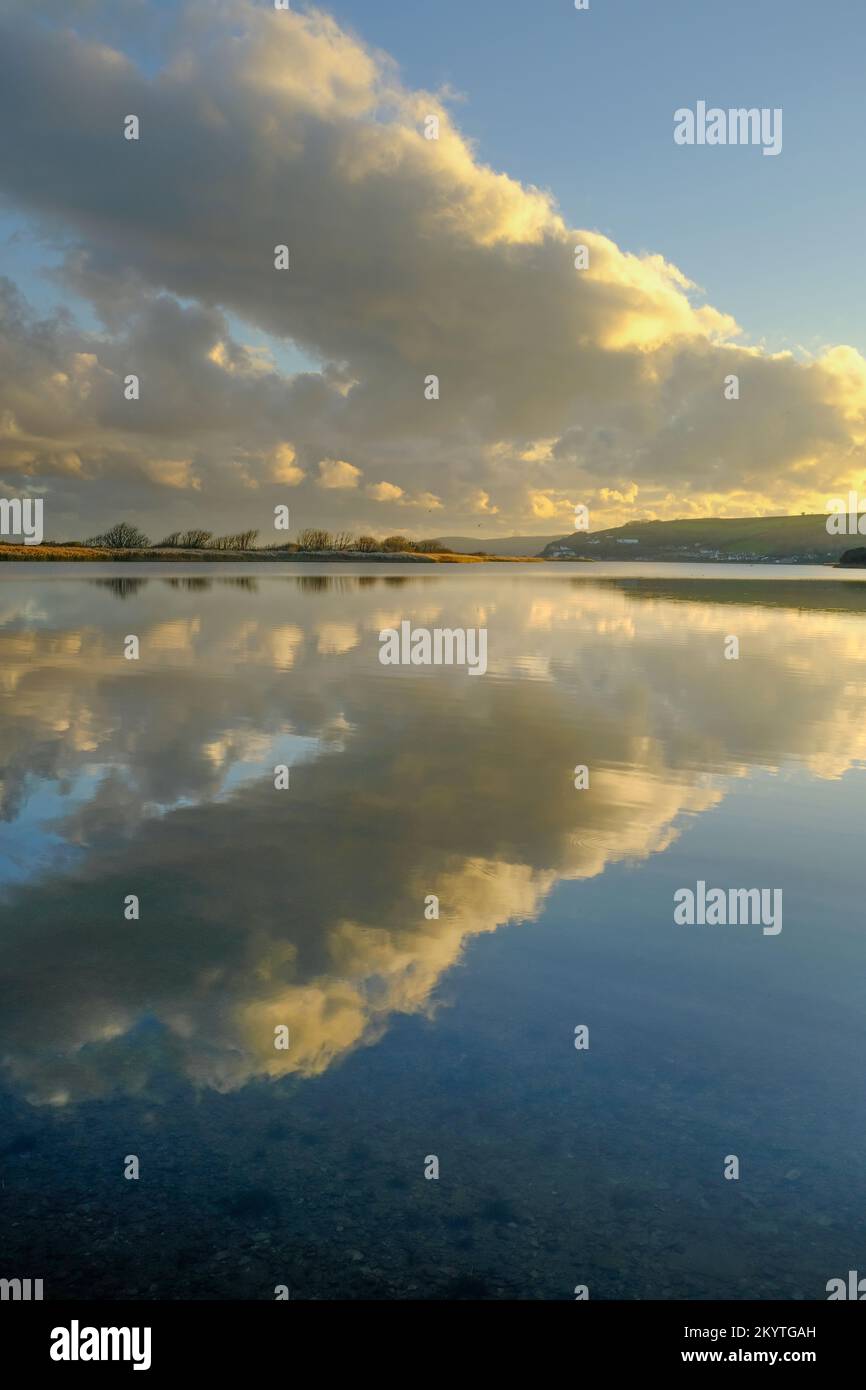 Late afternoon winter sun and clouds over the still, glassy waters of Slapton Ley, Start Bay, South Devon, UK Stock Photo
