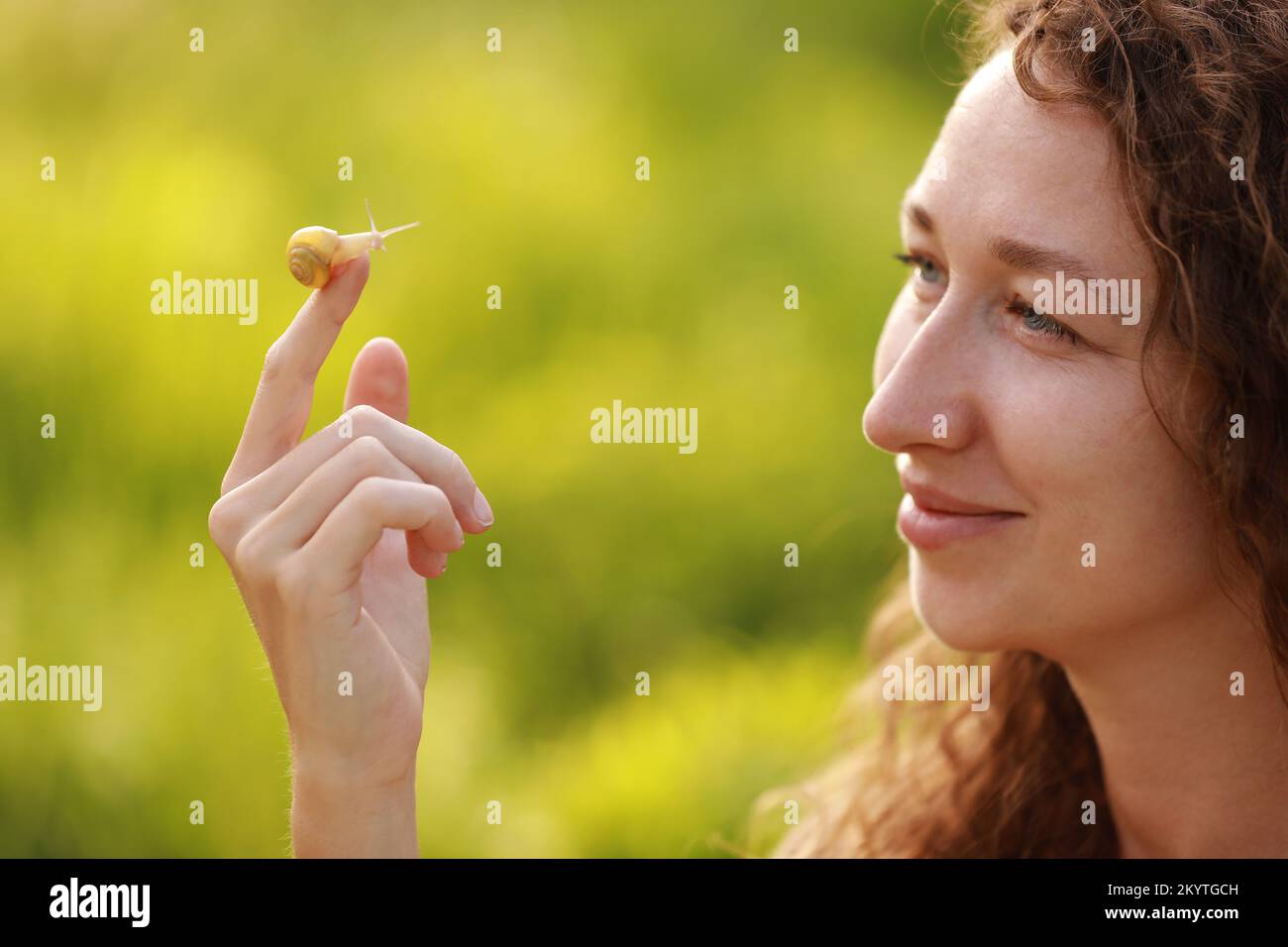 A small snail on the finger on green nature background, snail slime
