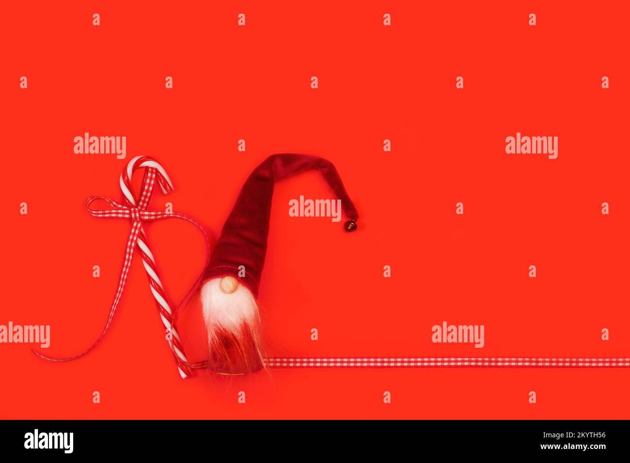 Red and white candy cane and Santa Claus doll on a red background with ...