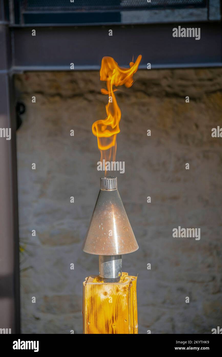 Flame on a torch kit on a wood in San Antonio, Texas. Selective foocus close-up of a fire flame on a torch against the blurred wall background. Stock Photo