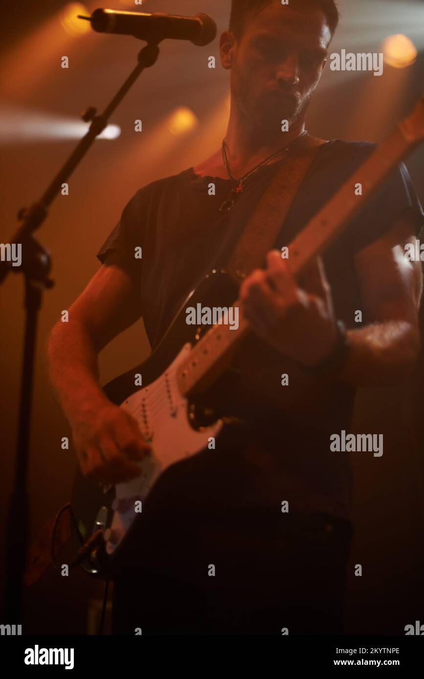 Music microphone, rock guitar and man playing electric instrument at metal band festival, dark concert or performance show. Creative stage shadow Stock Photo