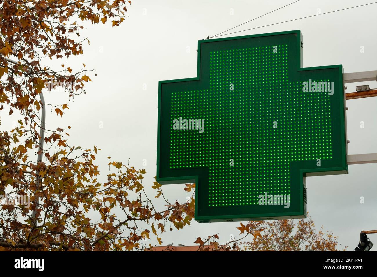 luminous green cross indicating that a pharmacy remains open in the city of Madrid Stock Photo