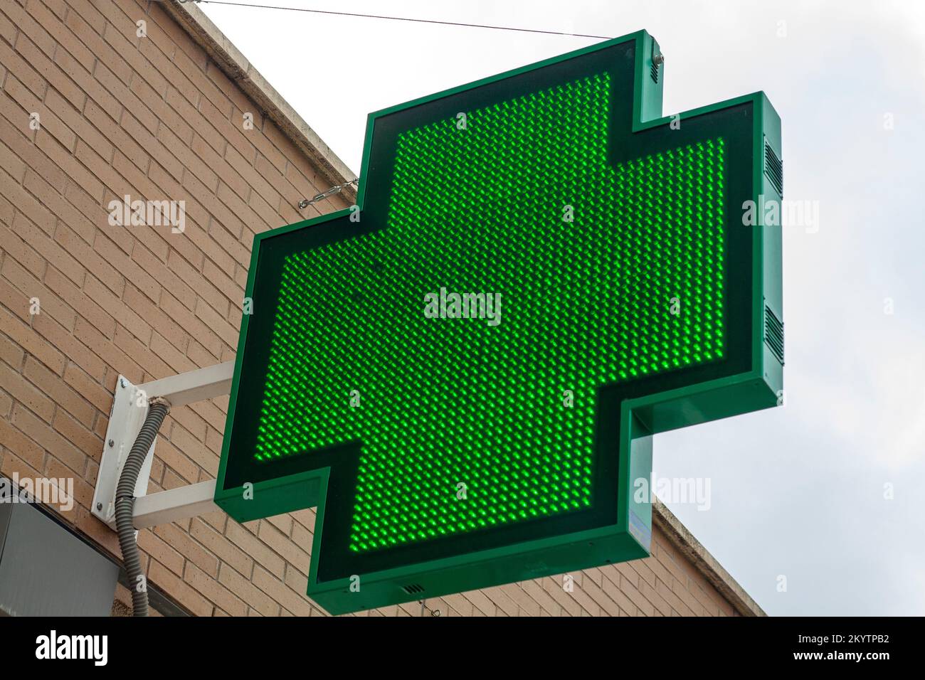 luminous green cross indicating that a pharmacy remains open in the city of Madrid Stock Photo