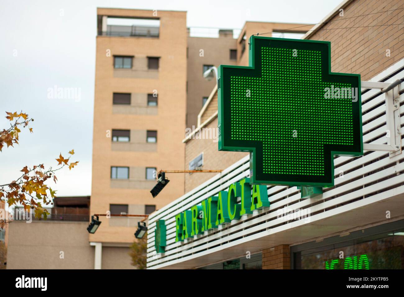 luminous green cross indicating that a pharmacy remains open in the city of Madrid Stock Photo