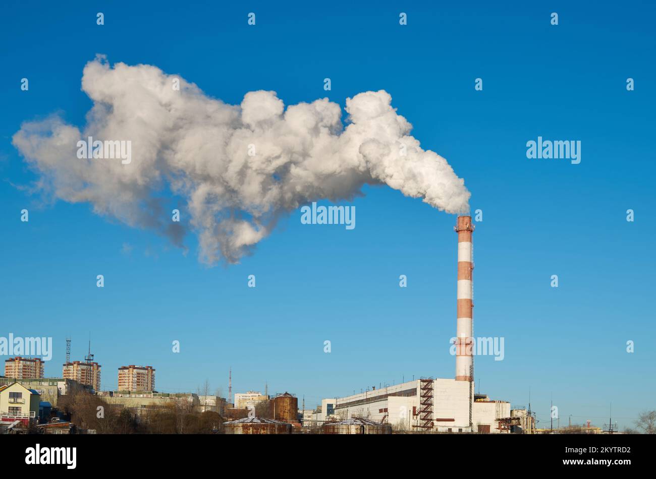 A tall brick chimney smokes into a clear blue sky Stock Photo - Alamy