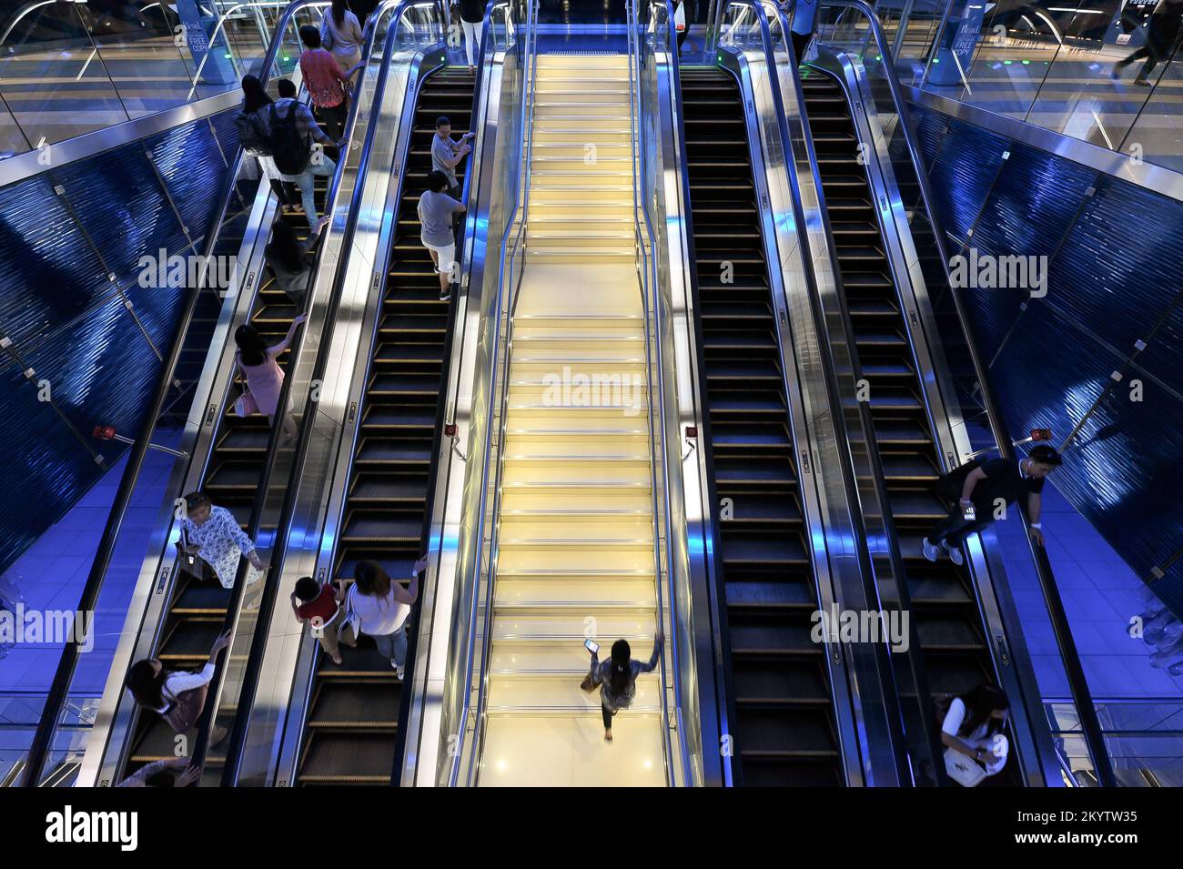 Dubai, United Arab Emirates - people ride escalators and climb stairs inside Dubai Metro Station. Futuristic interior design of BurJuman stop. Stock Photo