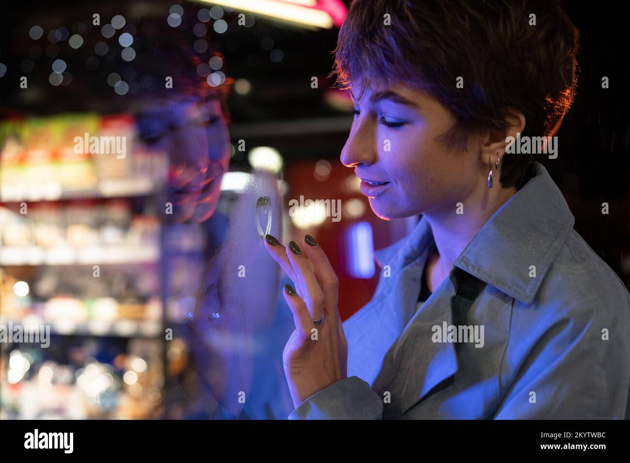 Thoughtful melancholic woman draw heart on steamy wet window think of ...