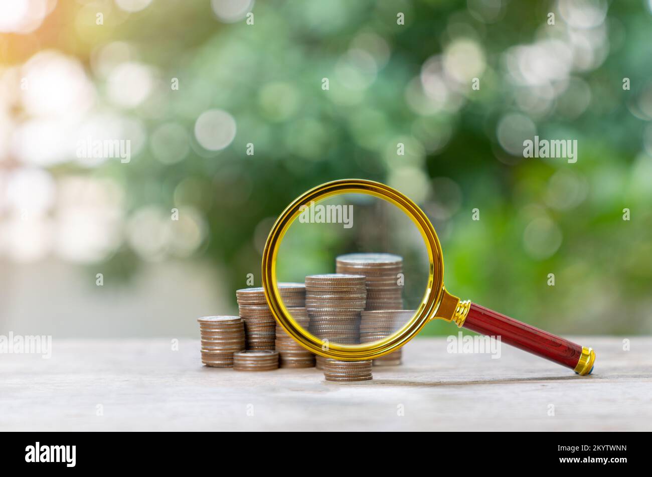 Magnifying glass zoom growing stacks of coins, conceptual image about ...