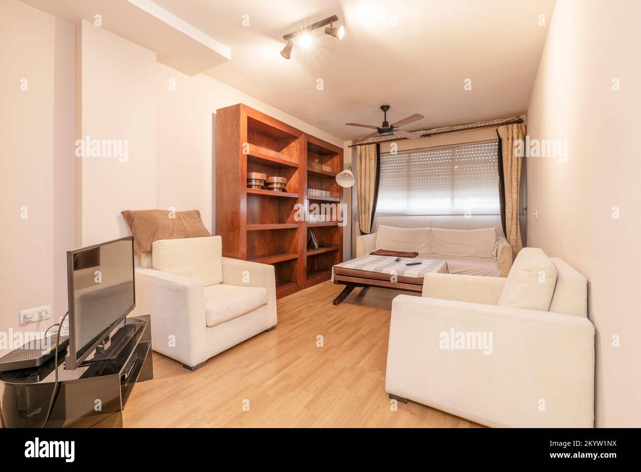 Living room with a wooden bookcase and a set of white fabric sofas Stock Photo