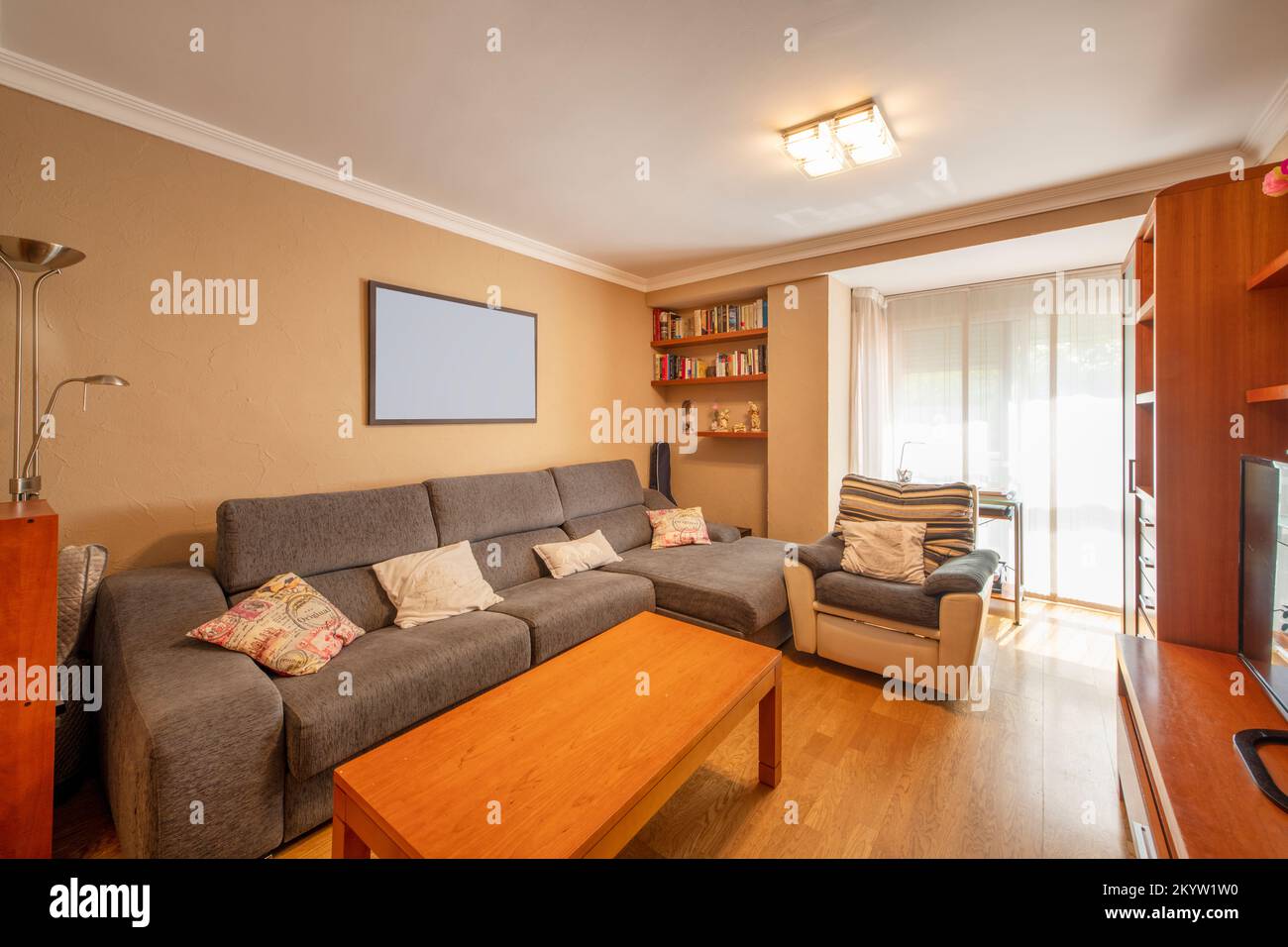 Living room of a house with a gray fabric sofa with chaise longue and cherry wood furniture Stock Photo