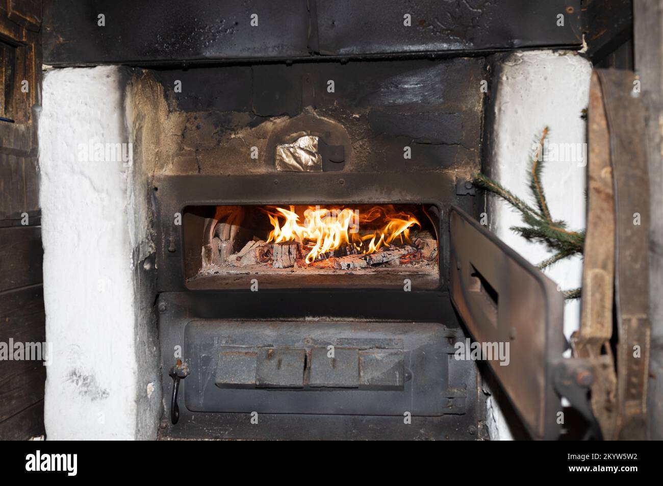 A bright fire burns in an old stove with an open metal door, copy space