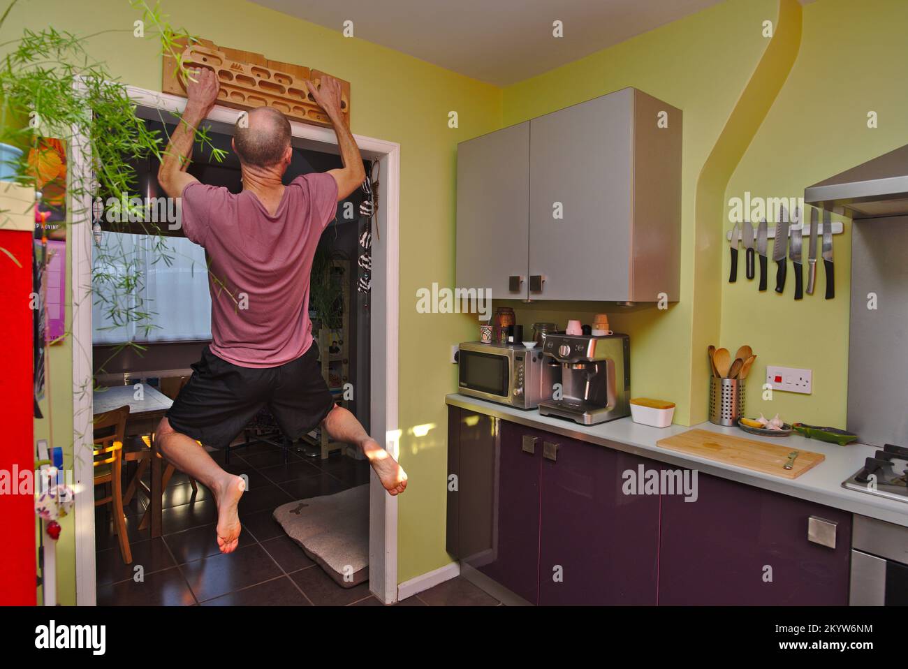 Climber strength training at home using a fingerboard in his kitchen. Stock Photo