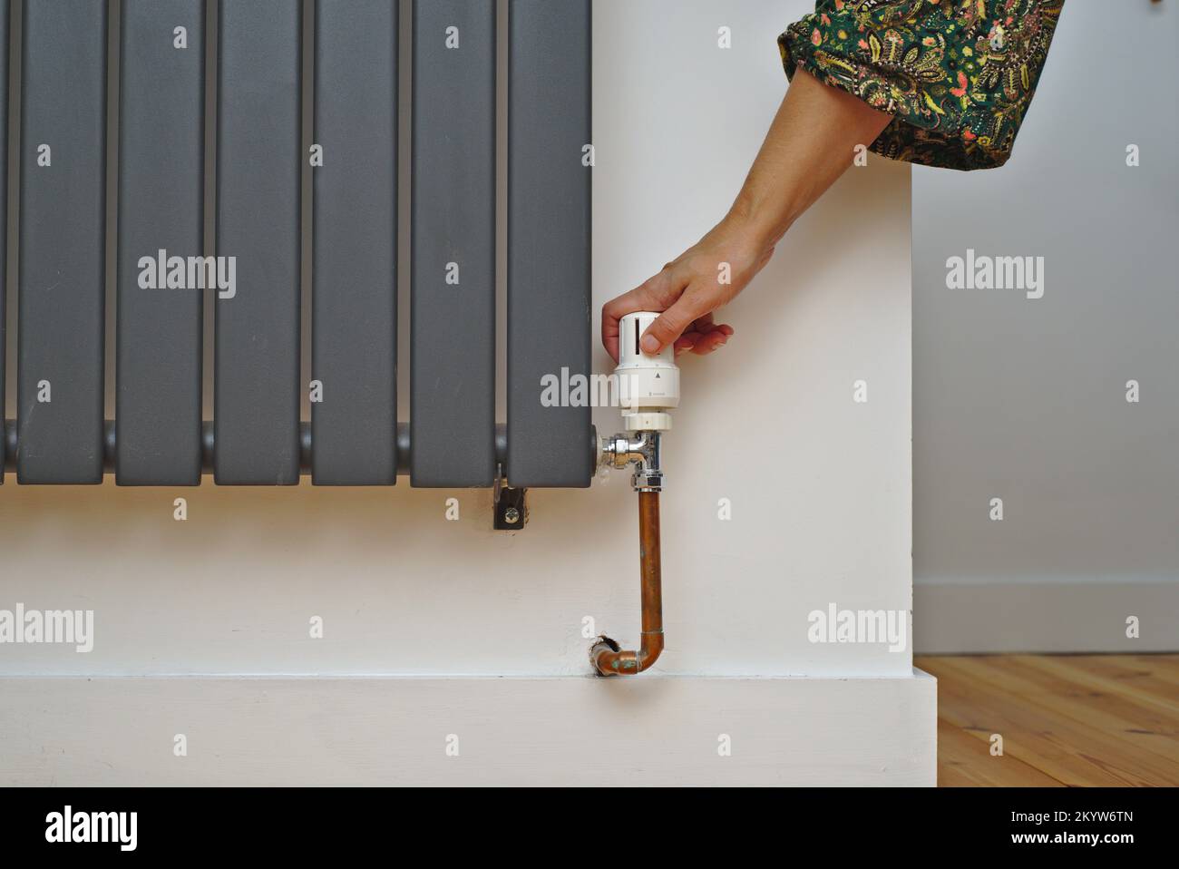 Adjusting the thermostat on a radiator to control room temperature