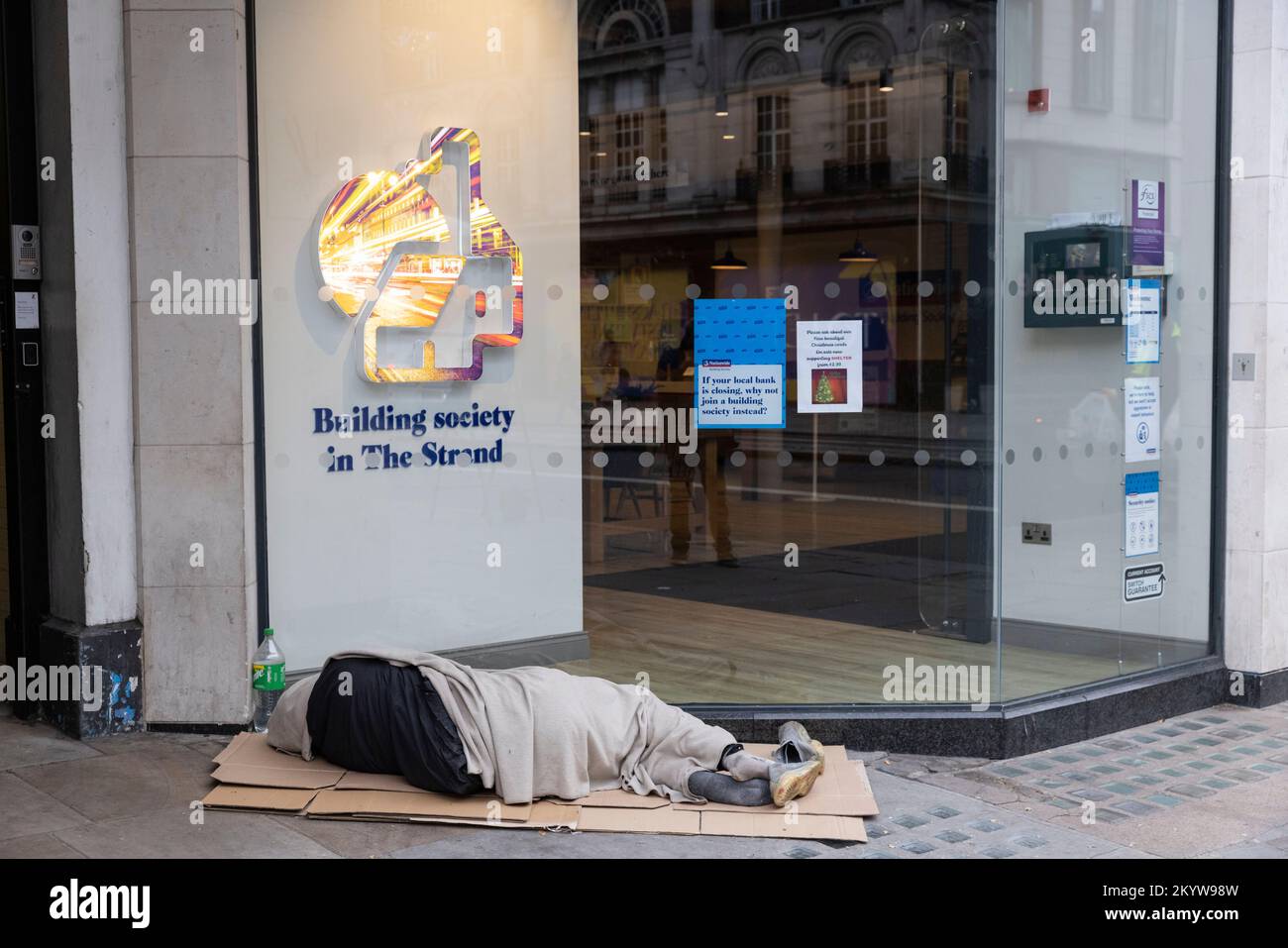 Homeless man sleeps outside the premises of a Nationwide Building Society, along the Strand in central London, United Kingdom Stock Photo