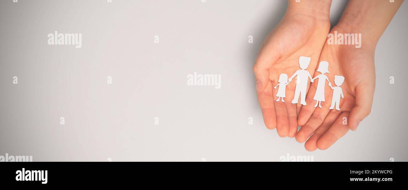 Family care concept. Hands with paper family silhouette on table. Stock Photo