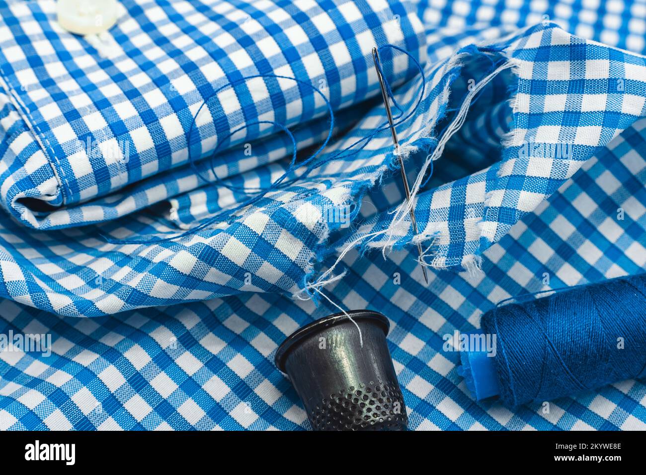 Needle and thread on a checkered fabric closeup. Seamstress or tailor