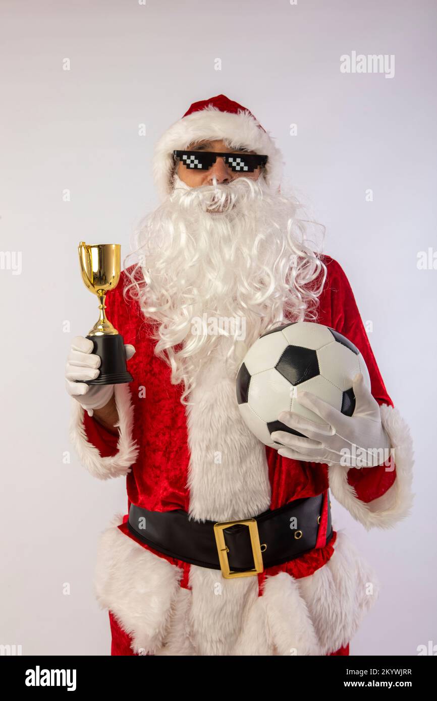 santa claus with sunglasses 'thug life' soccer ball and a trophy in his hand on white background Stock Photo