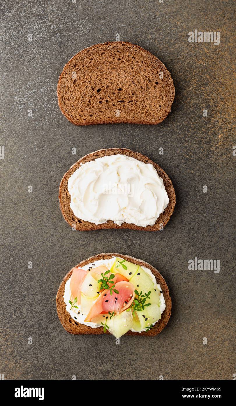 Three slices of rye bread showing three stages of making sandwich with ham and cucumber Stock