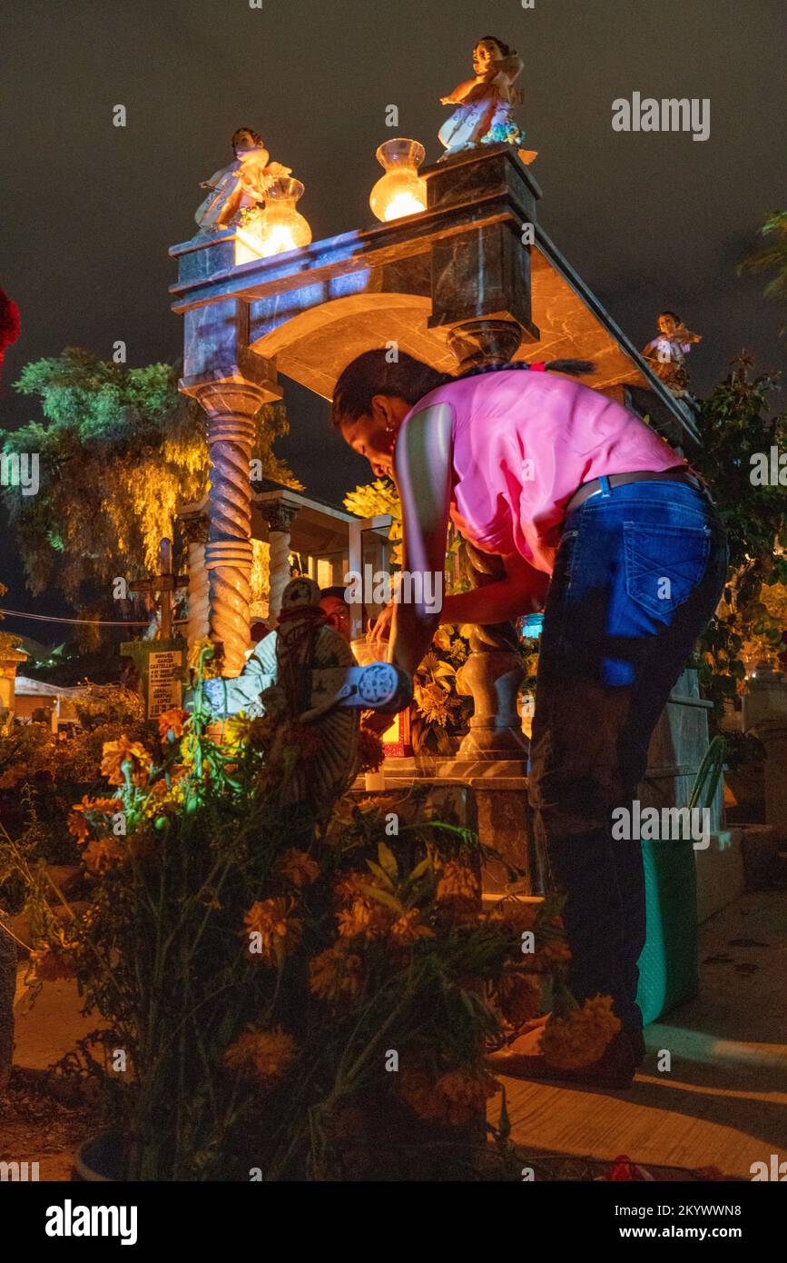 A woman decorates a grave in the Xochimilco Cemetery for the Day of the Dead or Dia de los Muertos in Oaxaca, Mexico. Stock Photo