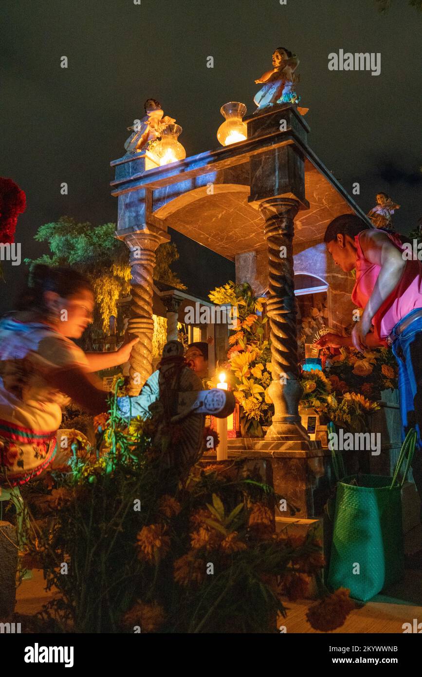 A woman decorates a grave in the Xochimilco Cemetery for the Day of the Dead or Dia de los Muertos in Oaxaca, Mexico. Stock Photo