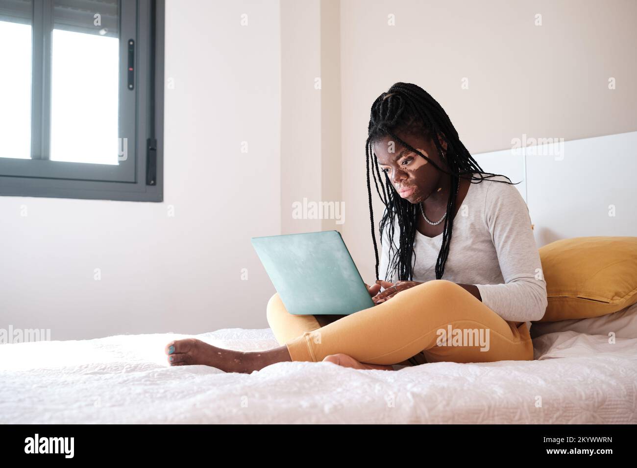 Black woman using netbook on bed at home Stock Photo