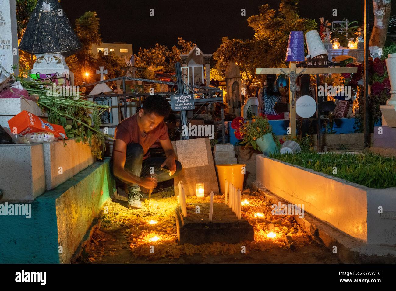 A man decorates a grave in the Xochimilco Cemetery for the Day of the Dead or Dia de los Muertos in Oaxaca, Mexico. Stock Photo