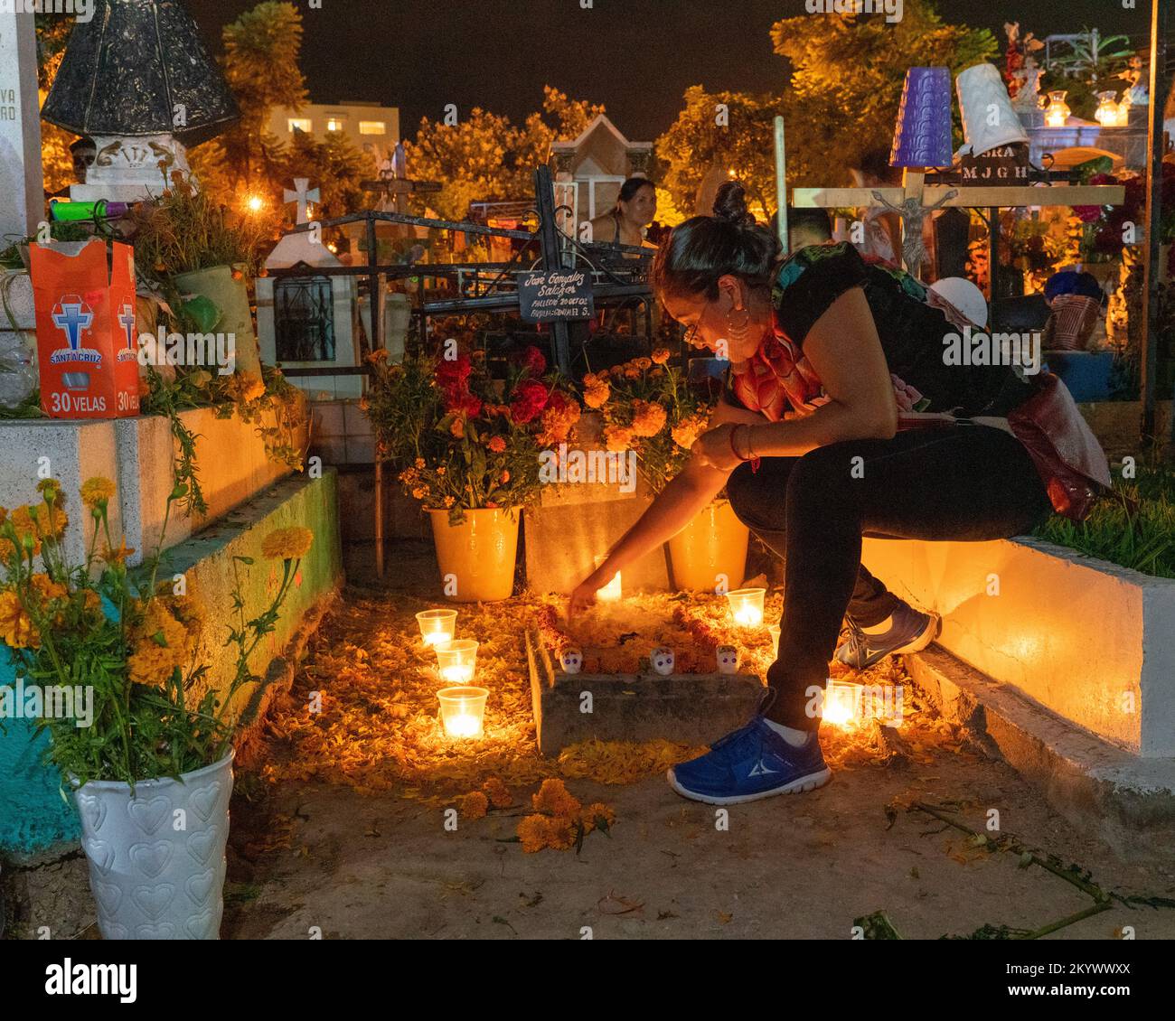 A woman decorates a grave in the Xochimilco Cemetery for the Day of the Dead or Dia de los Muertos in Oaxaca, Mexico. Stock Photo
