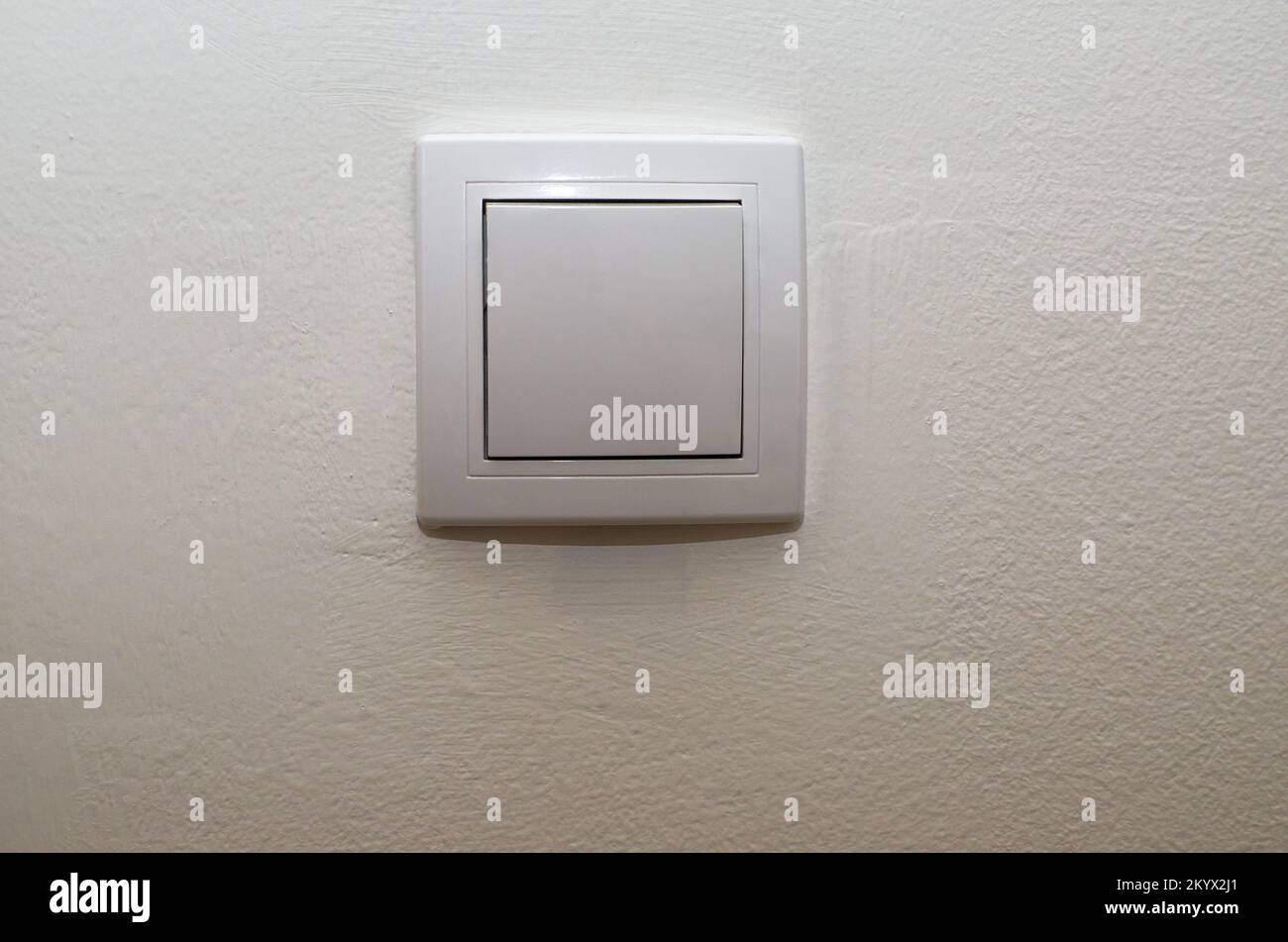 White plastic light switch on a white wall Stock Photo