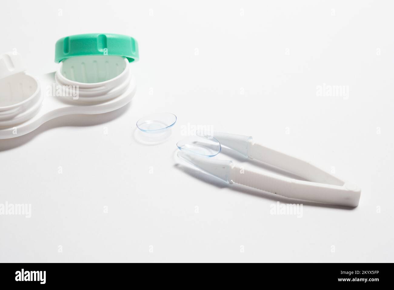 Contact lenses, tweezers and lens storage container on the table. Stock Photo