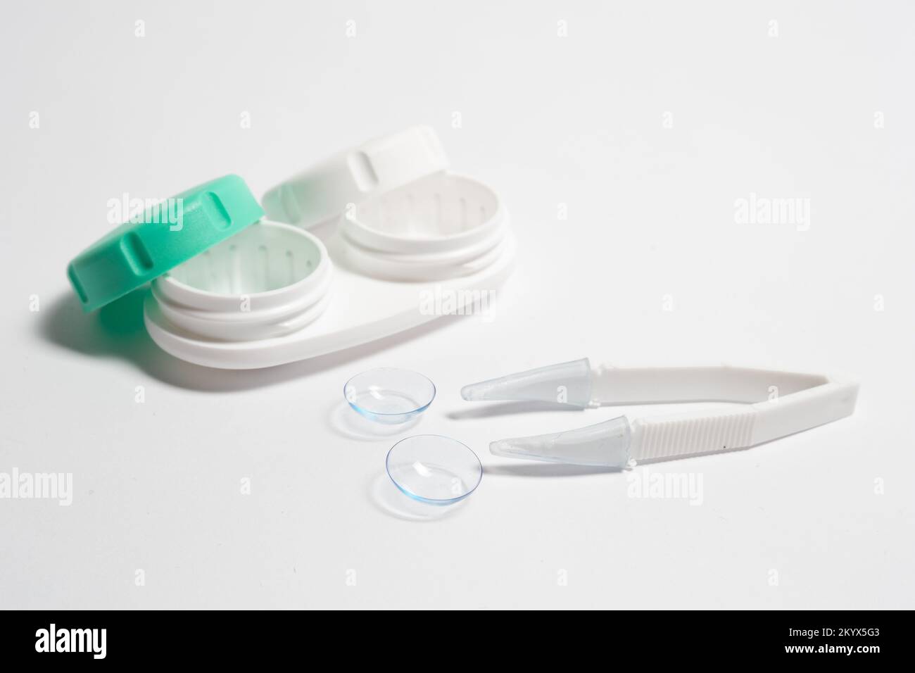 Contact lenses, tweezers and lens storage container on the table. Stock Photo
