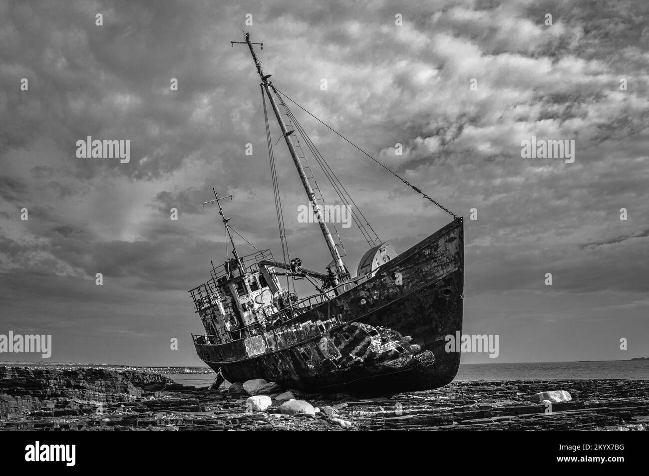 Moody image of a sunken rusty ship thrown on the shore. Rybachy Peninsula, Russia. Black and white. Stock Photo