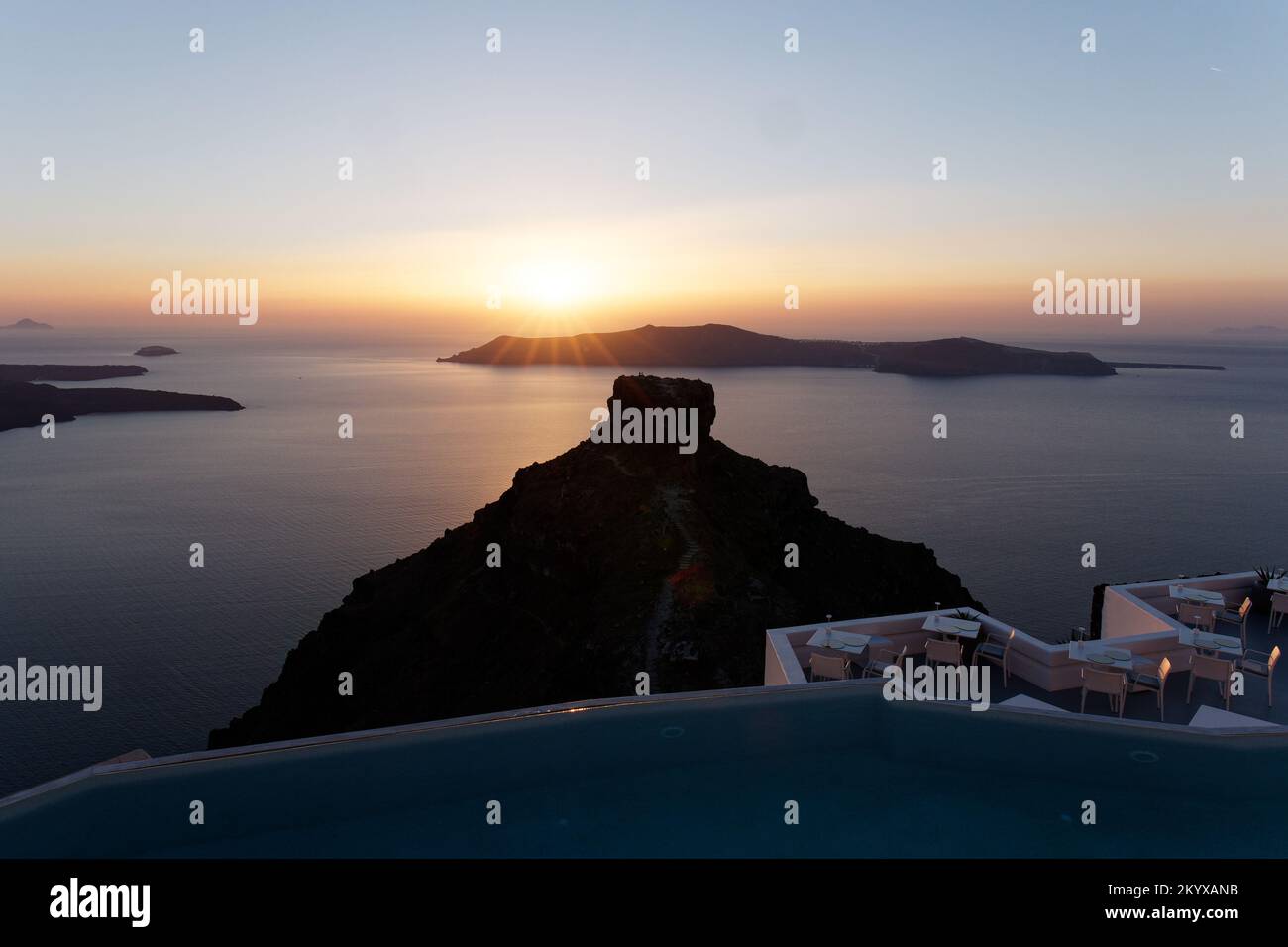 Sun setting over Thirasia with Skaros Rock foreground. Aegean Cyclades Island of Santorini, Greece. Stock Photo
