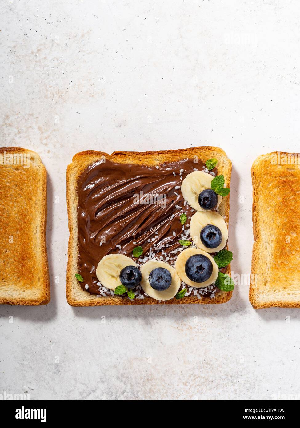Overhead shot of a wheat bread with chocolate spread, banana slices and berries on it Stock Photo