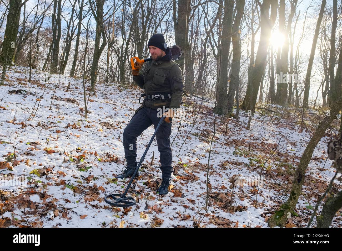 Man with metal detector and shovel in snowy forest Stock Photo