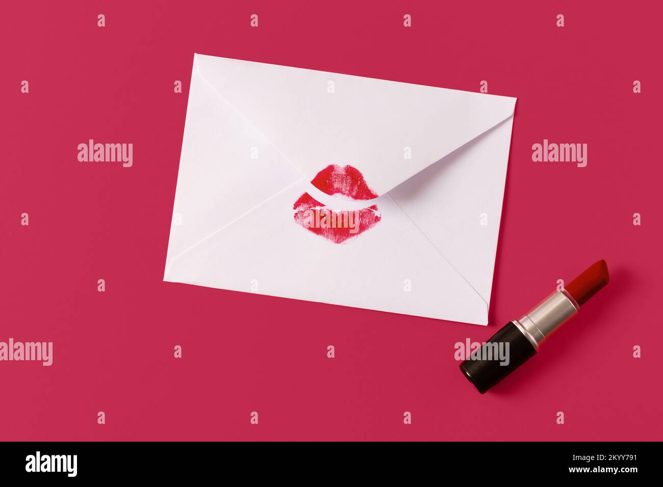 Red lipstick kiss on white envelope on magenta background. Love letter