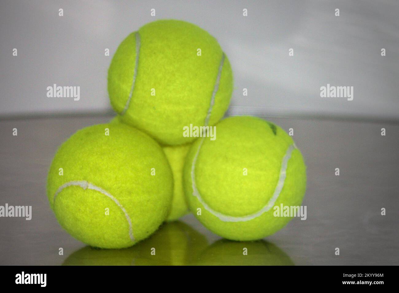 three tennis balls on a metal table Stock Photo