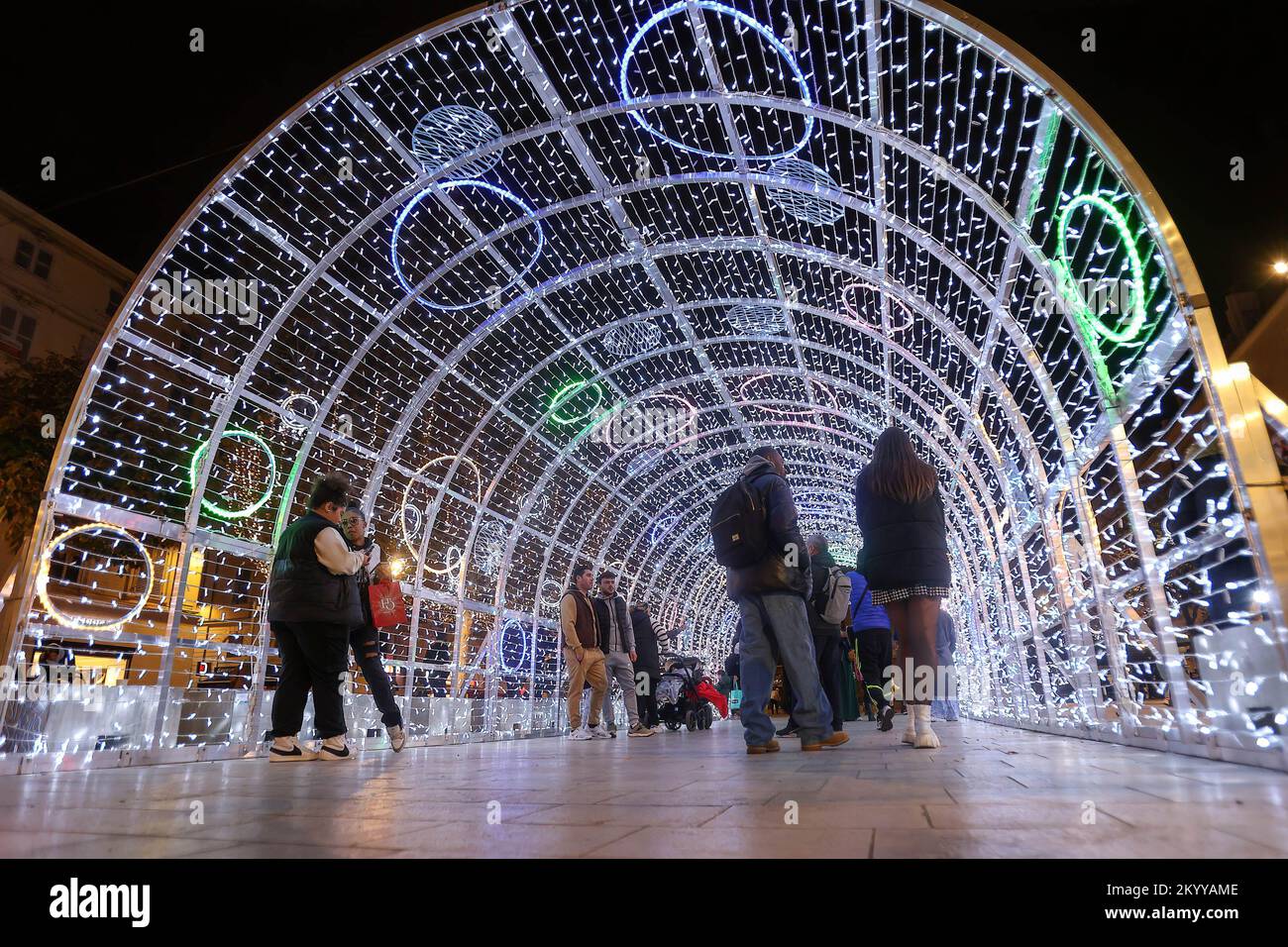 People walk under the Christmas lights in Marseille. With a shorter