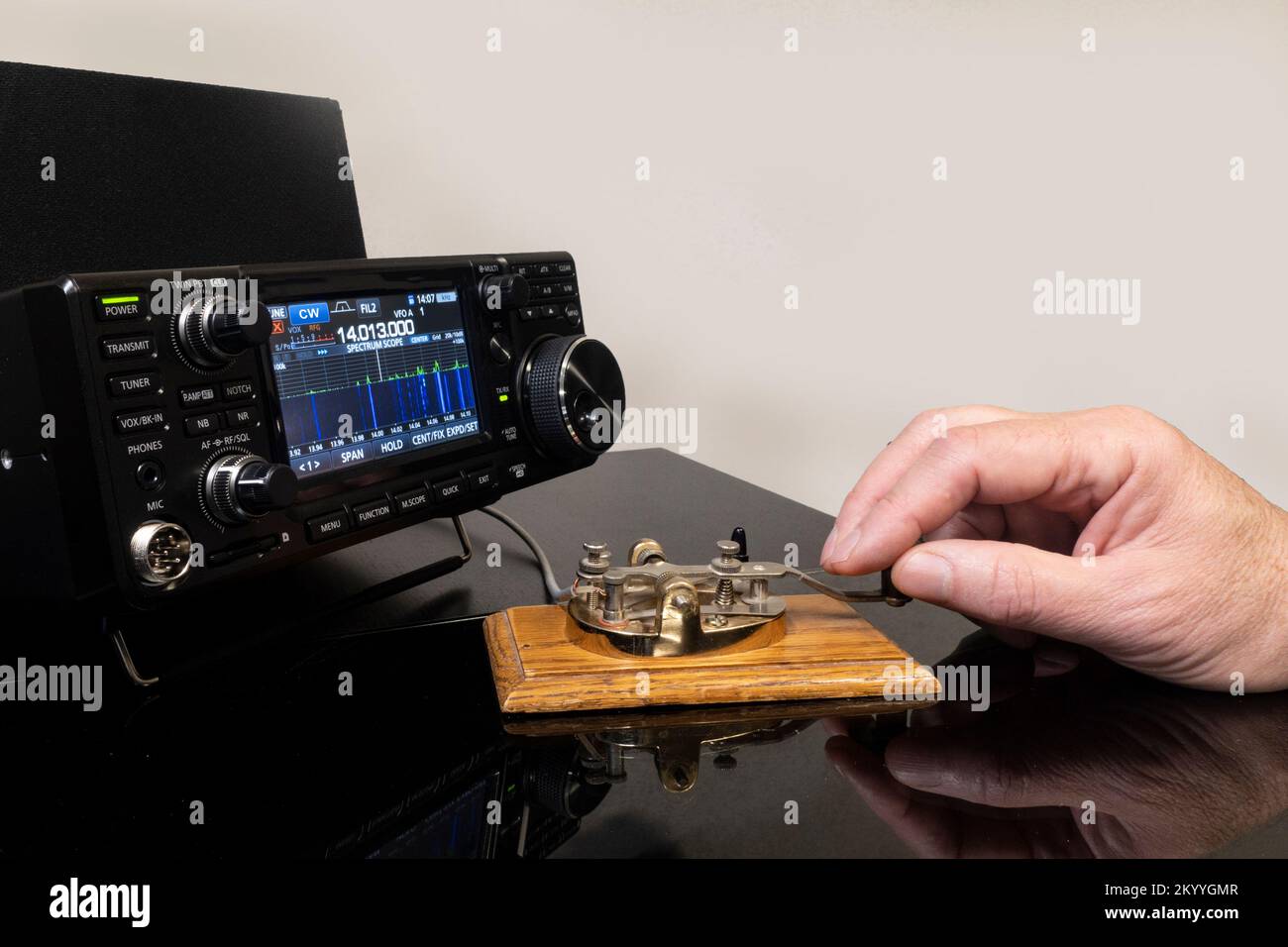 Man operating morse code key with modern radio transceiver Stock Photo