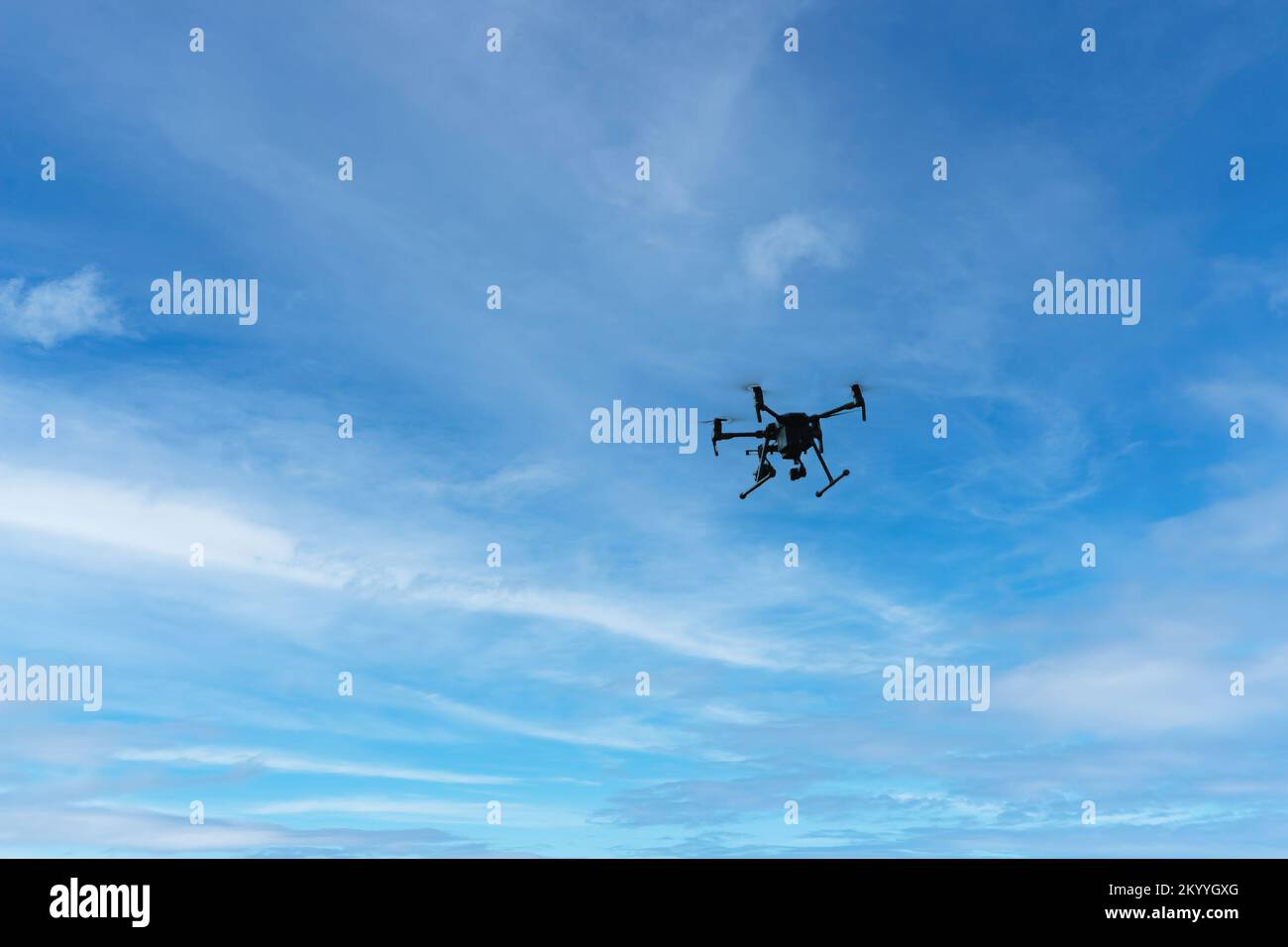 Drone on a background of blue sky with clouds. quadcopter in flight ...
